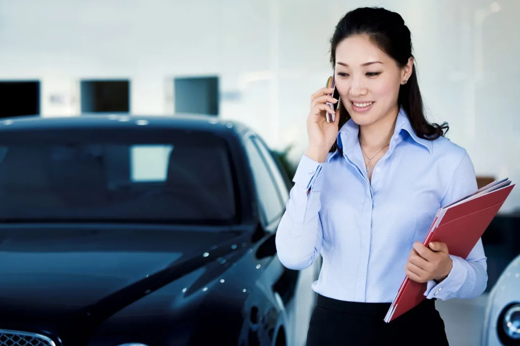 Insurance agent talking on the phone beside a car