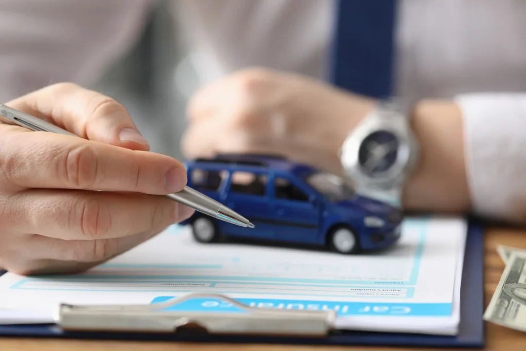 Agent signing a car insurance document beside a toy car