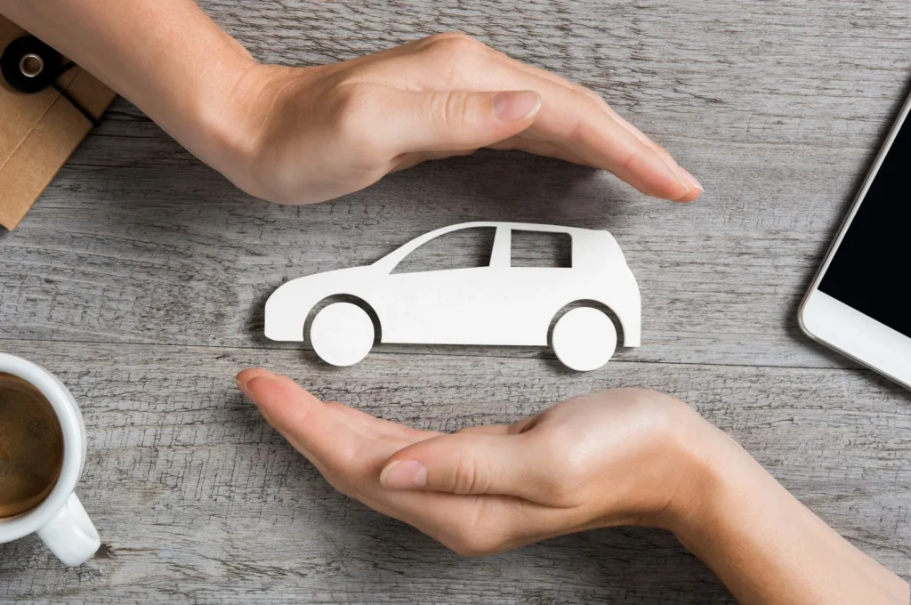 Hands protecting a small paper car