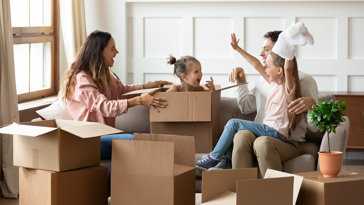 Family having fun unpacking moving boxes in their new home