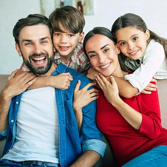 Smiling family of four embracing together